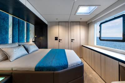 A modern and spacious bedroom with a large window overlooking the ocean, featuring a comfortable bed, built-in storage, and a minimalist design aesthetic.