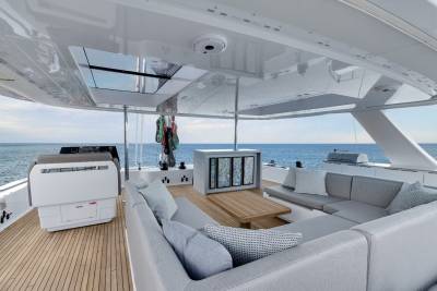 A modern, well-appointed interior of a yacht or boat, with a spacious living area, comfortable seating, and large windows offering a panoramic view of the surrounding ocean.