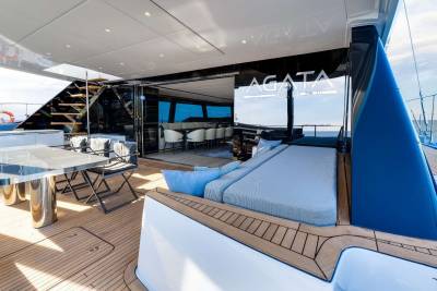 A modern and luxurious yacht interior with a spacious deck, comfortable seating areas, and large windows offering scenic views of the surrounding water.