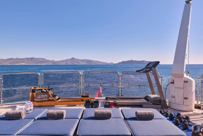 Enjoy a refreshing workout on deck with stunning ocean views and a backdrop of distant mountains.