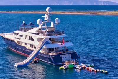 A luxurious yacht with a water slide and inflatable water toys awaits adventure on the clear blue sea.