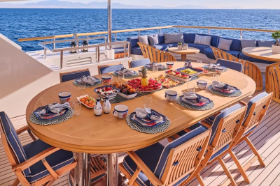 A beautifully set table on a yacht deck awaits a delightful meal with the ocean as a backdrop.