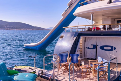 A luxurious yacht with an inflatable slide offers endless fun on the sparkling blue waters of a coastal town.