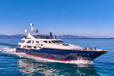 A luxurious navy and white yacht glides through the calm blue sea under a clear sky.