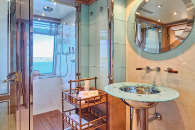 A luxurious yacht bathroom features a glass-enclosed shower with ocean views and a stylish pedestal sink.