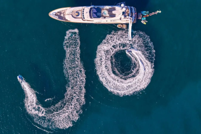A luxury yacht and jet skis create a celebratory "10" in the turquoise waters.