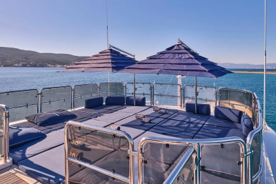 Relax on the spacious sundeck of this luxurious yacht, complete with plush cushions and ample shade from two large umbrellas.