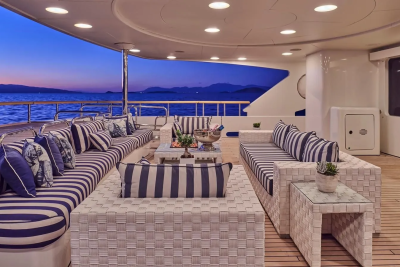 Elegant outdoor seating on a yacht deck offers a luxurious setting against a twilight ocean backdrop.