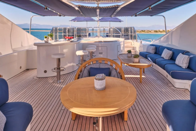 Relax on the spacious deck of this luxurious yacht, complete with a bar, hot tub, and comfortable seating overlooking the azure sea.