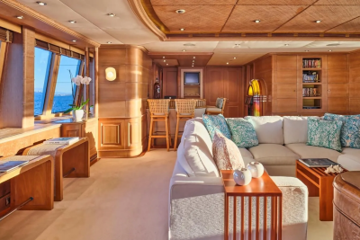 Luxurious yacht interiors feature warm wood paneling, plush seating, and large windows offering stunning ocean views.
