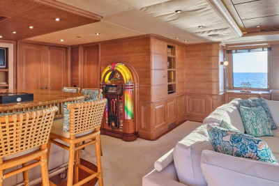 A vintage jukebox and plush seating create a retro-chic lounge aboard this luxurious yacht, overlooking the sparkling sea.