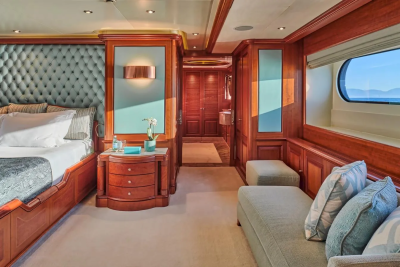 Luxurious yacht accommodations offer a serene retreat with tufted headboards, rich wood accents, and ocean views.
