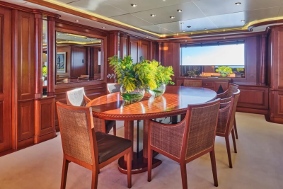 Rich mahogany paneling and a large circular dining table create an elegant atmosphere aboard this luxurious yacht.