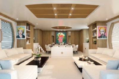 This luxurious yacht interior features a vibrant pop art collection, plush white seating, and a sophisticated dining area.