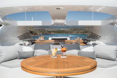 Two refreshing cocktails await on the teak table of this luxurious yacht, set against a stunning backdrop of the Mediterranean Sea.