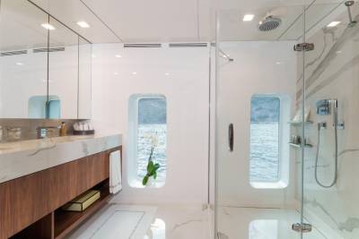 A luxurious yacht bathroom offers a serene escape with stunning ocean views through porthole windows.