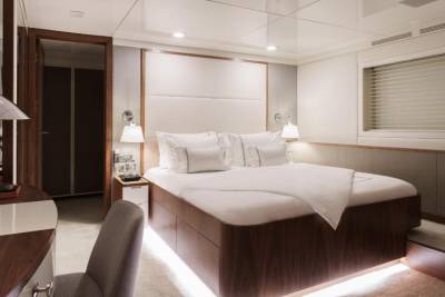 Luxurious yacht accommodations feature a plush king-sized bed with crisp white linens and elegant bedside lighting.