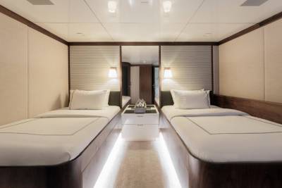Twin beds with crisp white linens are illuminated by soft lighting in this luxurious yacht cabin.