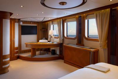 A cozy and well-appointed cabin interior with wooden furnishings, large windows, and a desk area.
