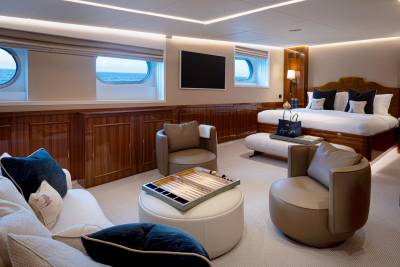 A luxurious and spacious cabin interior with wooden paneling, plush seating, and large windows offering a scenic ocean view.