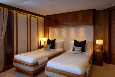 A cozy and well-appointed bedroom with twin beds, wooden cabinetry, and warm lighting creating a comfortable and inviting atmosphere.