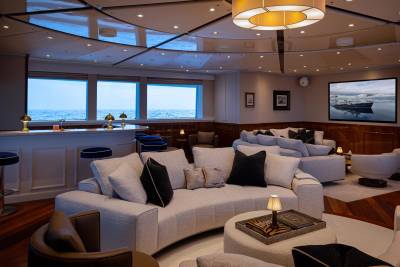 A cozy and luxurious living room with plush white sofas, a large circular window overlooking a scenic ocean view, and a warm lighting fixture creating a serene and inviting atmosphere.