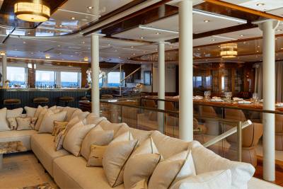 A luxurious and spacious interior with wooden beams, comfortable seating, and a bar area with a view of the outdoors.