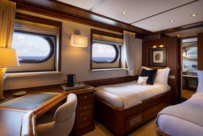 A cozy and well-appointed cabin interior with large windows offering scenic views, featuring a comfortable bed, wooden furnishings, and warm lighting.