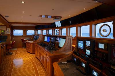 This appears to be the interior of a ship's bridge or control room, with a wooden paneled design and various instruments, screens, and equipment visible throughout the space.