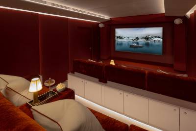 A cozy and inviting home theater setup with plush seating, a large screen displaying a scenic landscape, and various lighting and storage elements creating a warm and immersive atmosphere.