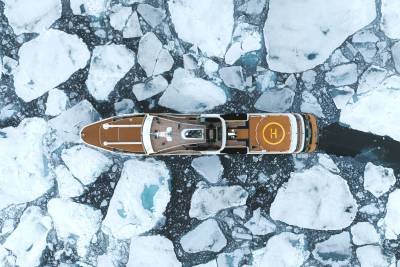 A small wooden boat floating on a frozen, icy lake surrounded by jagged, snow-covered rocks.