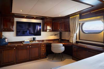 A cozy and well-appointed cabin interior with wooden cabinetry, a large television, and a comfortable chair positioned near a window, providing a scenic view.