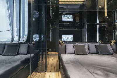 A modern and sleek interior design with a cozy seating area featuring plush gray sofas and a wooden floor, surrounded by glass walls that provide a panoramic view of the exterior.