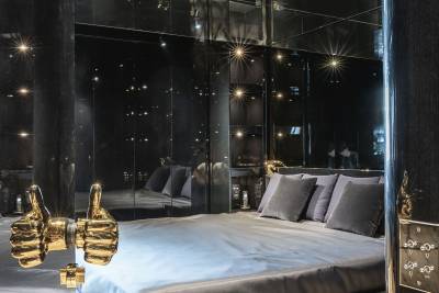 A luxurious bedroom with a large bed, plush bedding, and a mirrored wall creating a sparkling, starry atmosphere.