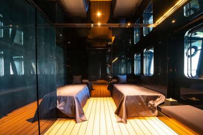 A dimly lit, cozy interior of a train car with wooden floors and benches covered in purple linens, creating an intimate and inviting atmosphere.