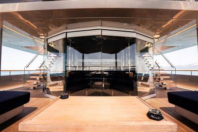 A luxurious and modern interior of a yacht, featuring a spacious deck with comfortable seating areas, a sleek design, and large windows providing a panoramic view of the surroundings.