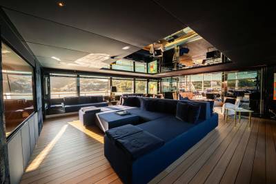 A modern and spacious living room with large windows offering a scenic view, featuring comfortable blue sofas and a minimalist design.