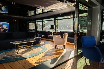A cozy and modern lounge area with comfortable seating, a wooden floor, and large windows offering a scenic view of the outdoors.