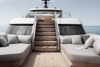 A luxurious yacht with a sleek, modern design, featuring a spacious deck with comfortable seating areas and a set of stairs leading to the interior.
