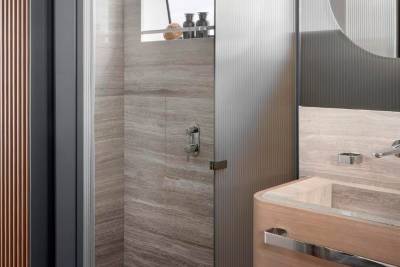 A modern bathroom with a glass shower enclosure, a wooden vanity, and a minimalist design aesthetic.