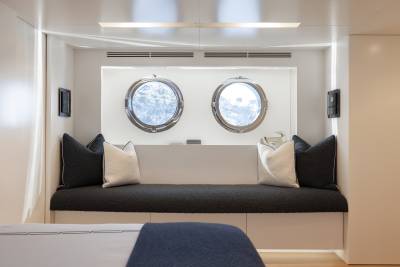 A cozy and inviting window nook with plush cushions and pillows, framed by two oval windows that allow natural light to flood the space.
