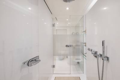 A modern, minimalist bathroom with a glass-enclosed shower, chrome fixtures, and recessed lighting creating a clean, bright, and spacious atmosphere.