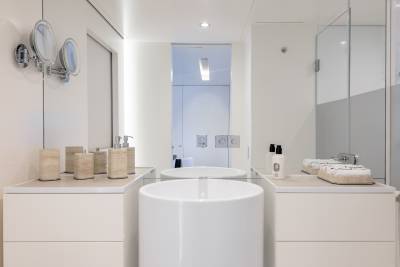A modern, minimalist bathroom with a freestanding bathtub, vanity units, and wall-mounted mirrors, creating a clean and serene atmosphere.