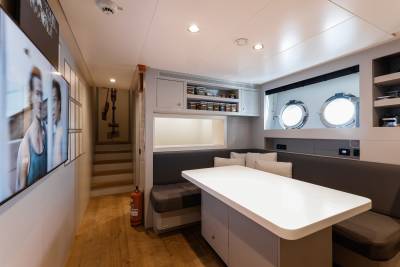 A modern and well-designed kitchen and dining area with white cabinets, a large countertop, and a cozy seating area with a sofa and artwork on the walls.