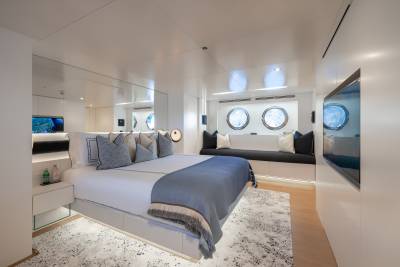 A modern and minimalist bedroom with a large bed, gray bedding, and mirrored walls that create a sense of depth and openness in the space.