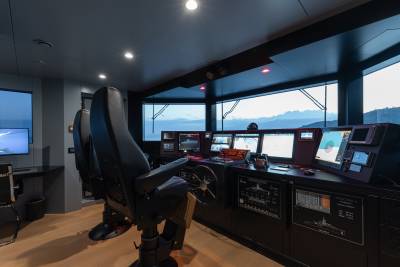 A dimly lit room with a large window overlooking a scenic landscape, filled with various electronic equipment and gaming peripherals, creating an immersive and technologically-advanced workspace.