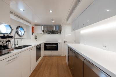 A modern, well-equipped kitchen with sleek white cabinets, stainless steel appliances, and a wooden floor.
