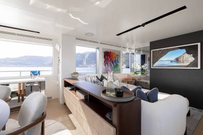 A modern and stylish living room with a large window overlooking a scenic landscape, featuring a wooden dining table, comfortable seating, and various decorative elements.