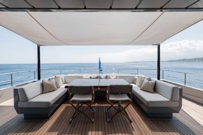 A modern, open-air deck overlooking a scenic ocean view, featuring comfortable outdoor furniture and a shaded canopy.