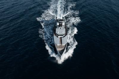A large, sleek yacht cutting through the deep blue waters, leaving a trail of white foam in its wake.